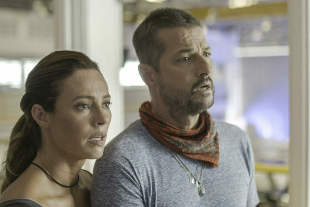 Moa (Marcelo Serrado) e Pat (Paolla Oliveira)  diante da tv assistem perplexos reportagem sobre a morte de Clarice (Ta&iacute;s Ara&uacute;jo).